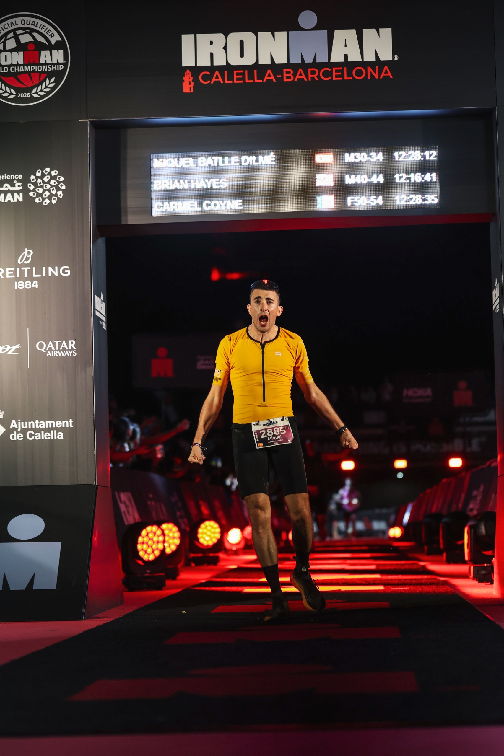 Miquel Batlle Dilmé cruzando la meta del Ironman Calella-Barcelona con su nombre y tiempo 12:28:12 en el marcador